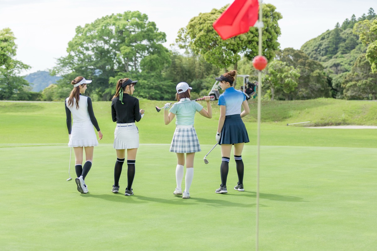 女性ゴルファー4人がゴルフコースを歩いている