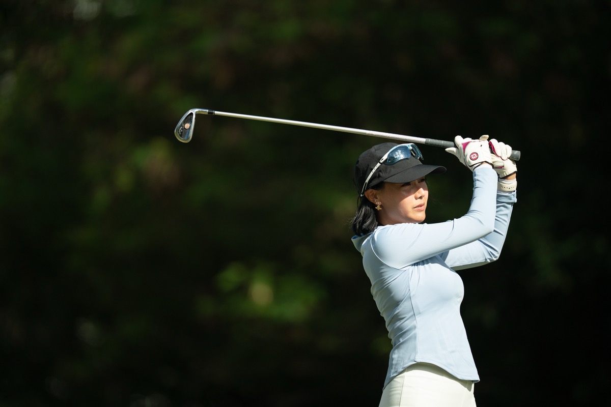 長袖インナーとパンツスタイルでスイングする女性