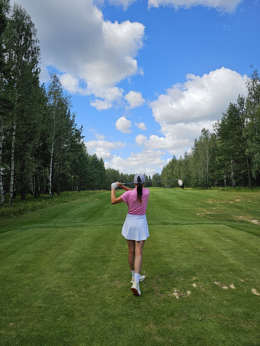 ゴルフコースでスイングする女性